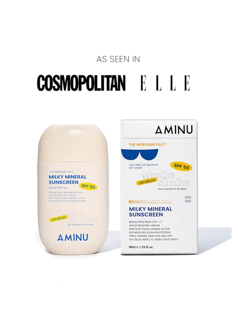 A product shot of AMINU Milky Mineral Sunscreen SPF 50 against a clean white background. The image features a rounded, beige-toned bottle next to its textured white outer carton. Above the product, the logos for Cosmopolitan and ELLE magazines are displayed under the text 'AS SEEN IN'. The packaging highlights key features like broad-spectrum protection, ultrafluid texture, and water resistance. Best Mineral Sunscreen